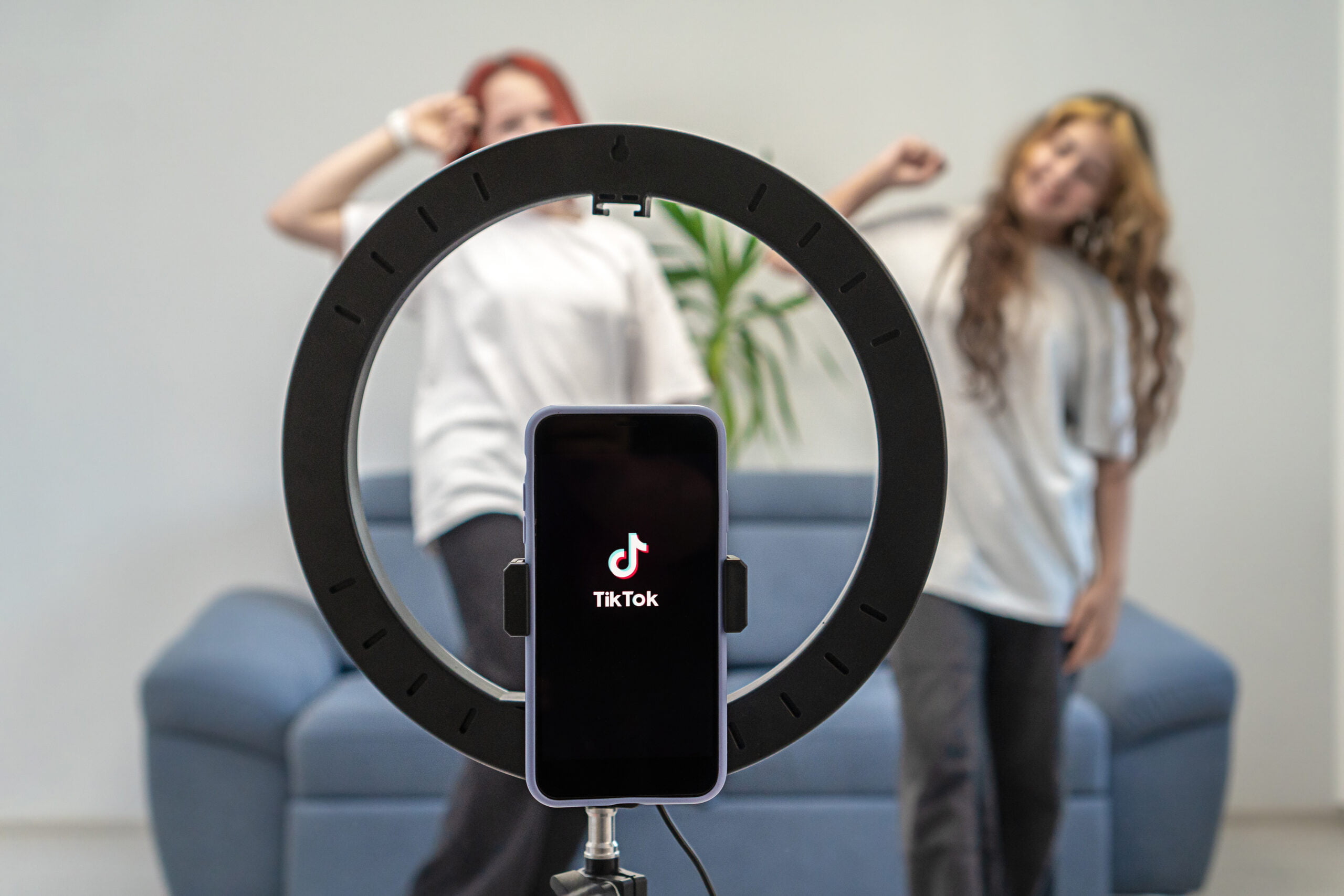 Two teenage girls are filming a video for their Tiktok vlog at their home. Tiktok logo on a phone on a tripod. Gen Z talent people play video selfie shoot app for show share viral story. Turkey, Istanbul, May 29, 2022.